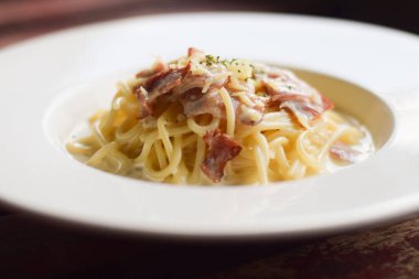 Tahta masadaki beyaz tabakta spagetti.