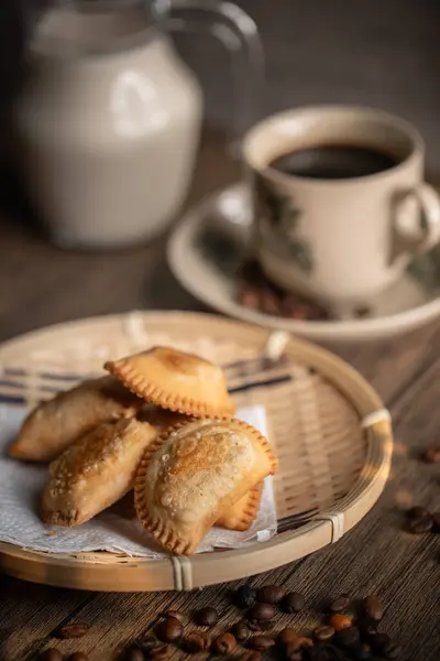 Fried Curry Puffs on a Rattan Plate with a Cup of Coffee. Malaysian Snacks. Malaysian Breakfast. Asian Foods.