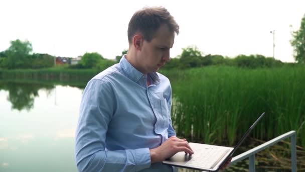 Een Man Werkt Met Een Laptop Bij Rivier — Stockvideo