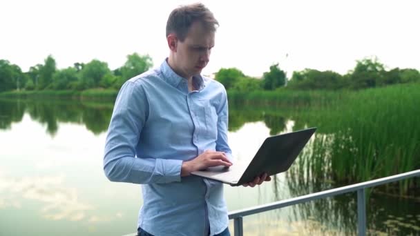 Bir Adam Nehrin Yanında Dizüstü Bilgisayarla Çalışıyor — Stok video