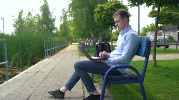 Hombre Trabaja Con Portátil Mientras Está Sentado Banco Río — Vídeos de Stock