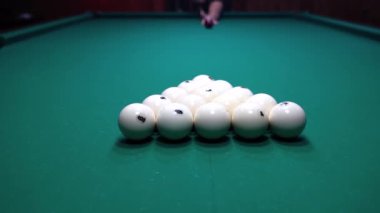 Bir adam bilardo oynuyor, oyuna top piramidini kırarak başlıyor.