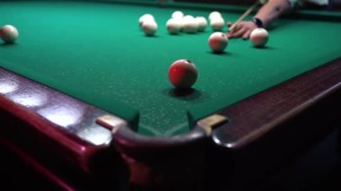 Bir adam bilardo topuna vurup diğerini vuruyor ve topu cebine atıyor.