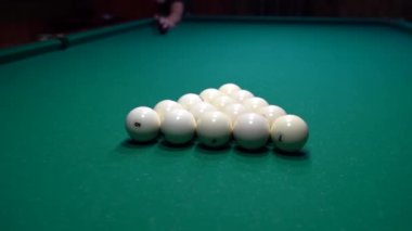 Bir adam bilardo oynuyor, oyuna top piramidini kırarak başlıyor.