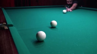 Bir adam bilardo topuna vuruyor.