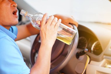 Asyalı sarhoş adam arabada içmek için bir şişe brendi tutuyor. Alkol ya da viski içerken araba kullanmayı bırak. Kazaya yol açan aracı kullanmak yasadışı ve tehlikeli..               
