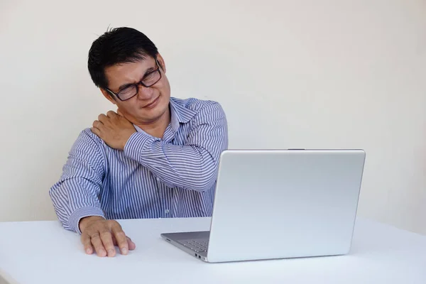 Asian man feels hurt his neck and shoulder during working on laptop computer for long time. Concept : Office syndrome. Health problem. Self massage to relief. Hard working