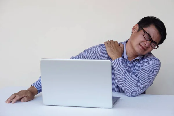 Asian man feels hurt his neck and shoulder during working on laptop computer for long time. Concept : Office syndrome. Health problem. Self massage or streching to relief.