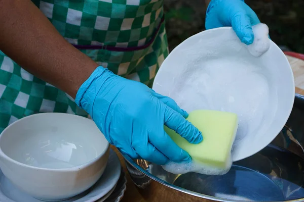 Hands use sponge scrubber to clean dish. Concept, daily chore, household cleaning kitchen utensils. Wear protective gloves to protect hands from chemical substances allergy.