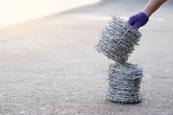 Closeup worker hand holds roll of barbed wire. Concept, construction tool. Barbed wire is used for make fences , secure property ,make border to show the territory of  area.