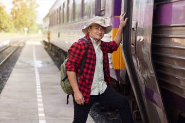 Asian man traveller gets on the local train. Concept, travel by train in Thailand . Railway station ransportation. Alone journey. Weeken, holiday or vacation trip. 