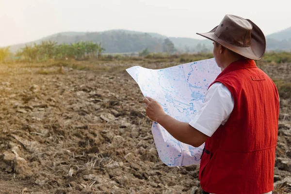 アジア人探検家は帽子 赤いベストシャツを着て 土地の境界を探索するための地図を保持しています コンセプト 土地計画 不動産の探索 地質調査区域だ 土地で宝探し アドベンチャーライフスタイル — ストック写真