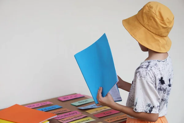 Young boy holds book to read. Practice reading skill from textbook and word cards. Concept, Education, learning and studying process. Kid reads book with concentration.