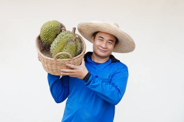 Yakışıklı Asyalı çiftçi şapka takıyor, mavi gömlek giyiyor, elinde durian meyvesi sepeti var. Kavram, tarım işgali. Taylandlı çiftçiler ekonomik ve ihracat meyveleri olarak durian meyveleri yetiştiriyor              