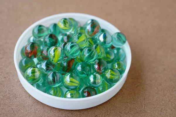 白い皿の上に透明な大理石のガラス球を丸める コンセプトは 指で撃つ弾丸としての子供のおもちゃ Diy作品の装飾用の装飾ボール 科学実験装置 — ストック写真