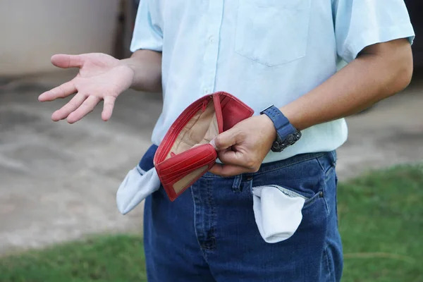 Closeup man holds empty red wallet to show that he has no money. Concept, Poor, bad economic crisis. Financial problems. Broke or less money at the end of month.