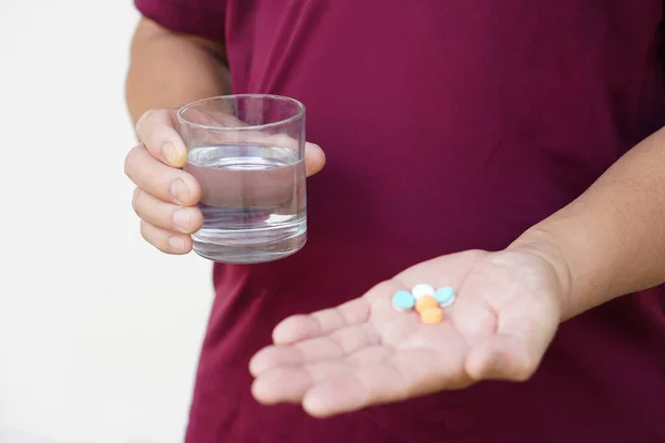 Closeup hand holds glass of water to take medicine. Concept : Health care, health problem, sickness and remedy. Basic self take care , treatment at home when get sick. Take pills under prescription.