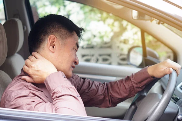 Asian man  feels hurt his neck and shoulders during his long driving in car. Concept  Injury, pain or tired from driving. Unsafe driving during abnormal symptoms. Transport, healthcare. Health problem