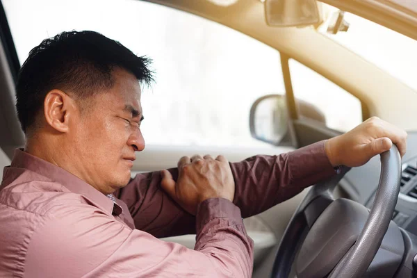 Asian man feels hurt his arm during driving long way. Concept  Injury, pain or tired from driving. Unsafe driving during abnormal symptoms. Transport, healthcare. Health problem