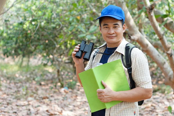 Азиатский Исследователь Носит Синюю Шапку Держит Бинокль Лесу Обследовать Ботанические — стоковое фото