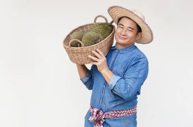 Yakışıklı Asyalı çiftçi şapka takıyor, mavi gömlek giyiyor, elinde durian meyvesi sepeti var. Kavram, tarım işgali. Taylandlı çiftçiler ekonomik ve ihracat meyveleri olarak durian meyveleri yetiştiriyor   