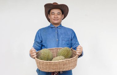 Yakışıklı Asyalı çiftçi şapka takıyor, mavi gömlek giyiyor, elinde durian meyvesi sepeti var. Kavram, tarım işgali. Taylandlı çiftçiler ekonomik ve ihracat meyveleri olarak durian meyveleri yetiştiriyor.    