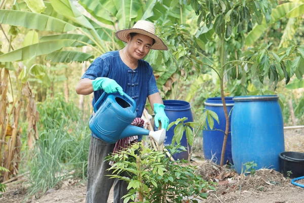 Uomo Asiatico Giardiniere Tiene Annaffiatoio Blu Innaffiare Piante Giardino Concetto — Foto Stock