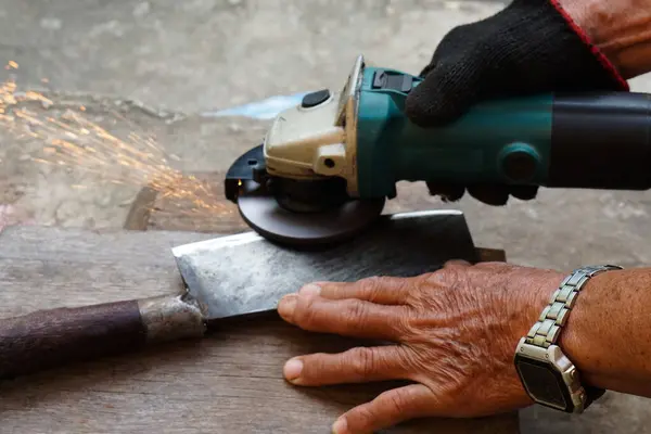 stock image Close up mechanic hands use electric grinders to sharpen iron knife. Concept, traditional style of fixing tool, maintenance tools for cooking, make knife sharp ,not dull for long live using. 