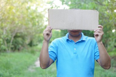 Adam, mesaj ya da kelime eklemek için boş kağıt tutuyor. Parkta duruyor. Kavram, protesto. İmzala ve bildir. Duyuru. Bilgi veriliyor.  