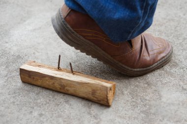 Yakından ayakkabı giyen adam, tahta üzerinde paslı metal çiviye basıyor. Kavramsal, tehlikeli, tehlikeli tetanos riski. Dikkatli ol ve inşaat alanında yürürken etrafına bak.. 