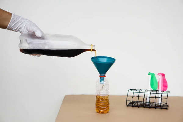 科学実験のための漏斗瓶に注ぐためにソフトドリンク水のボトルを手を閉じてください — ストック写真