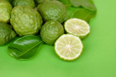 Yeşil arka planda Bergamot meyveleri ve yaprakları. Konsept, ekşi tadı olan bitkisel meyveler, gıda çeşnisi olarak pişirilebilir ve spa, aroma olarak kullanılabilir.  