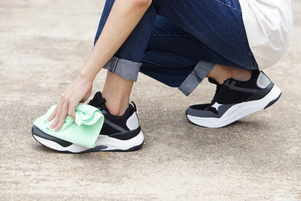 Close up hand uses soft cloth to wipe dirt or dust on shoe. Concept, footwear take care. Maintenance for clean, sanitary and hygiene for long life using. Healthy wearing footwears. sneakers.