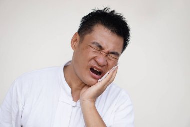 Asyalı adam acı verici diş ağrısı, diş eti iltihabı, yanağına dokunmak için elini kullan, gözlerini kapat, ağzını aç. Konsept, diş sağlığı sorunu ve sağlık hizmetleri.                                  