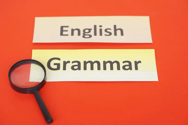 Word cards English Grammar, magnifying glass on red background. Concept, language learning. Find English grammar stucture. Education. School subjects.