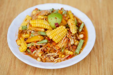Lezzetli baharatlı mısır salatası, tatlı mısır karışık papaya salatası ve beyaz tabak. Kavram, Tayland yemeği tarzı, Tayland 'da popüler bir menü. Orijinal papaya Som Tam 'dan uyarlanmıştır..            