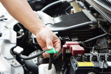 Tamircinin eli otomobilin soğutucu seviyesini kontrol etmek için araba motorunda bir şişe su açıyor. Konsept, kontrol ve bakım servisi.