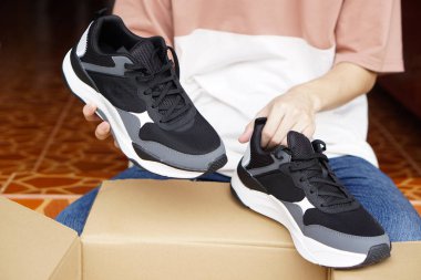 Yakın mesafedeki müşterinin elinde karton kutulardan aldığı yeni ayakkabılar var. Konsept, ayakkabı, online veya ayakkabı dükkanlarından alınan malların durumunu kontrol etmek. Şık ayakkabılar..                 