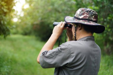 Asyalı ekolojist ormandaki doğayı incelemek için dürbün kullanır. Kavram, doğa keşfi. Ekoloji dersi. Hobi aktivitesi, yaşam tarzı. Çevreyi keşfet. Yalnız seyahat etmek.            