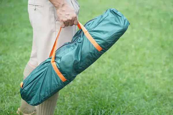 Close up man carry a green bag of tent to go camping outdoor. Concept, camping tent, equipment as accomodation for temporary outdoor sleeping as hiking or backpacking.