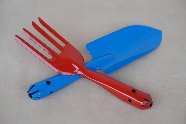 Blue shovel and red digging fork . Concept, gardening tools. Prepare equipment to planting or seeding.