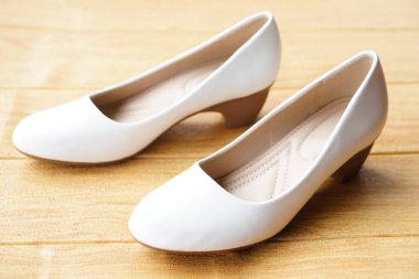 Ahşap zemin üzerinde kadın için beyaz ayakkabılar. Ofis çalışanları için kavram, moda, resmi ve kibar ayakkabılar ya da hemşireler için ofiste ya da hastanede beyaz üniformayla uyumlu ayakkabılar giymek. Ayakkabılar.