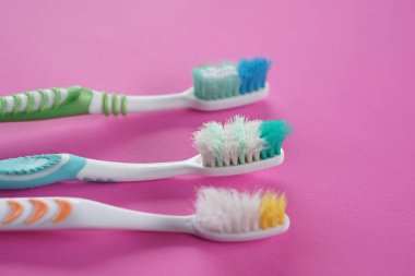 Pembe arka planda üç adet kullanılmış eski diş fırçası. Kavram, fırça dişleri için alet. Diş fırçasını diş temizliğinin verimliliği için kullanarak yenisini uzun zamandan değiştirmem gerekiyor..               