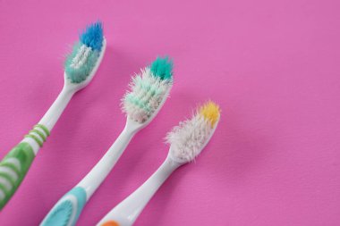 Pembe arka planda üç adet kullanılmış eski diş fırçası. Kavram, fırça dişleri için alet. Diş fırçasını diş temizliğinin verimliliği için kullanarak yenisini uzun zamandan değiştirmem gerekiyor..               