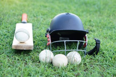 Kriket takımları, kask, kriket topları ve çimlerde sopa. Konsept, spor malzemeleri. İyi bilinen bir spor dalı. Kriket, bir sahada on bir kişilik iki takım arasında oynanan bir beysbol oyunudur.