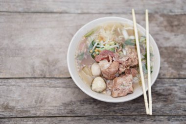 Köfteli domuz çorbası ve kasede sebzeler, tepesinde çubuklar, eski ahşap arka plan. Konsept, geleneksel yemek. Tayland 'daki erişte dükkanlarında yemek pişirebilen veya sipariş verebilen favori menü.. 