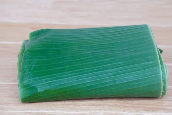 Folded banana leaves for food wrapping on brown wooden background. Concept, package container from nature, safe for wrapping food. Eco friendly and safety for consumers.