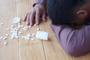 Depresyondaki adam aşırı dozda ilaç kullanarak intihara teşebbüs etti. Masaya yüzüstü. Kavram, depresyon, panik, zihinsel veya fiziksel sağlık, hayal kırıklığı, hayat sorunları intihara yol açar.