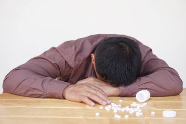 Depresyondaki adam aşırı dozda ilaç kullanarak intihara teşebbüs etti. Masaya yüzüstü. Kavram, depresyon, panik, zihinsel veya fiziksel sağlık, hayal kırıklığı, hayat sorunları intihara yol açar.  