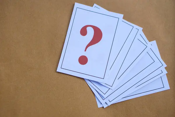 Pile of overlapped paper cards of red question marks, brown background. Overlapping. Concept. Teaching aid. Education materials for doing activity or playing games about find answers.